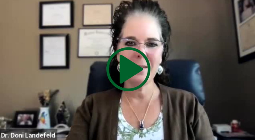 A person with glasses and a green play signDescription automatically generated