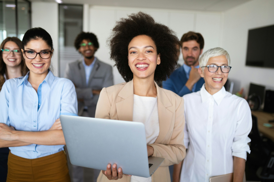 In a meeting room, co-ed confident leaders are smiling and standing 
