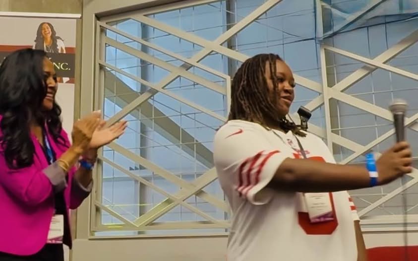 Kim Peterson applauding student leaders sharing their voice on stage — empowering authentic youth leadership.