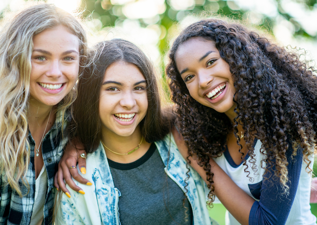 Tween and teen girls smiling and supporting one another—symbolizing healing, confidence, and belonging through Kim Peterson’s Fear to Freedom to R.I.S.E.™ empowerment program based on the WHOLE YOU® + H.O.P.E.™ approach.