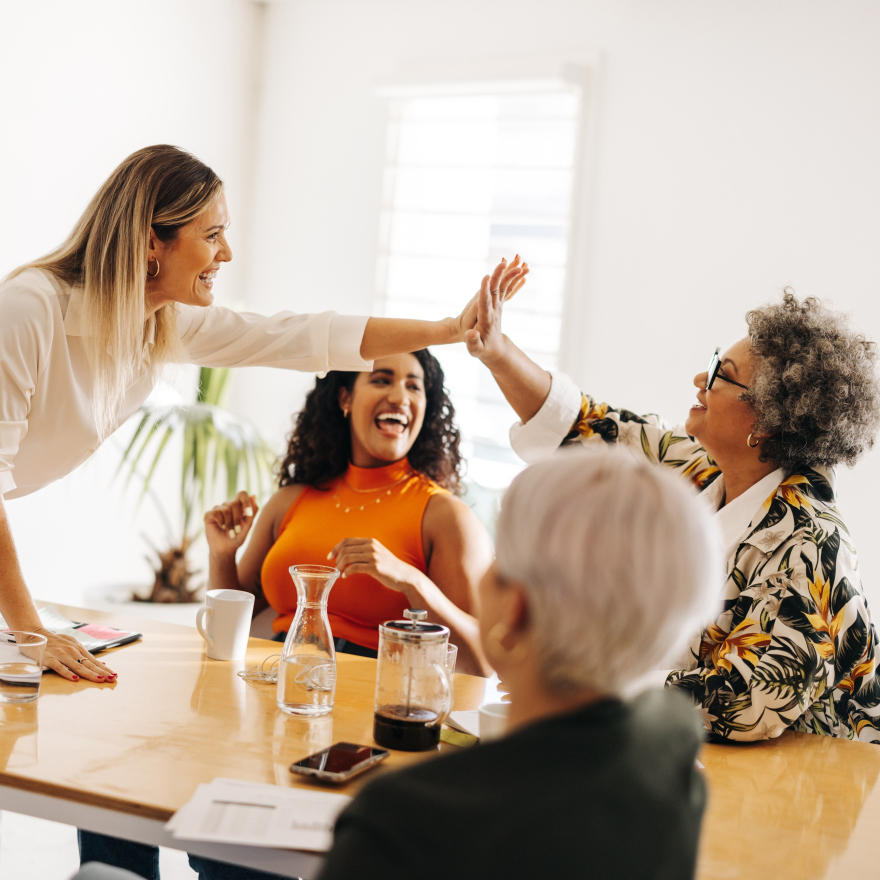 Diverse group of women in leadership celebrating success during a coaching session. Captures authentic confidence, connection, and joy as they strengthen leadership branding, executive presence, and resilience. Reflects career advancement, teamwork, and personal growth inspired by WHOLE YOU Life and Leadership Coaching with Kim Peterson, Trauma-Informed Leadership Brand Coach.