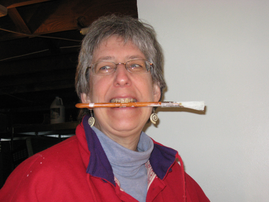 Barb Bickford holding a paintbrush in her teeth