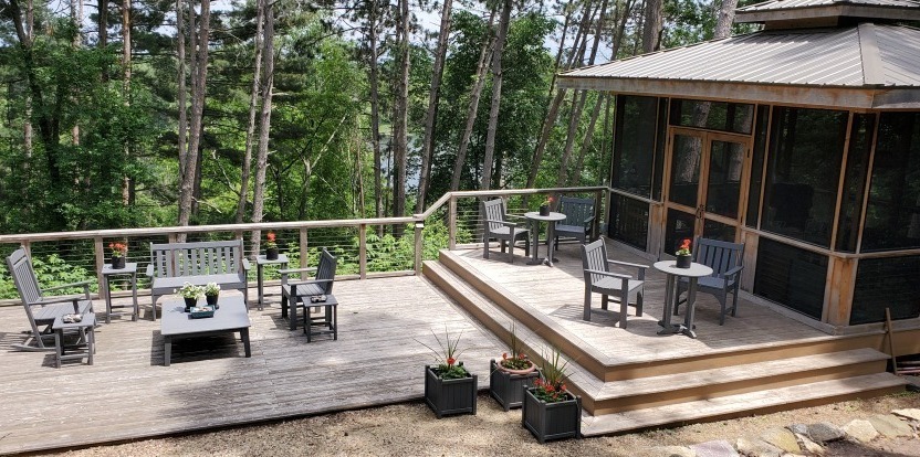 A large deck overlooking a lake, with deck chairs and a gazebo on the side