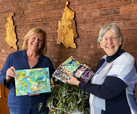 Two women holding pieces of art