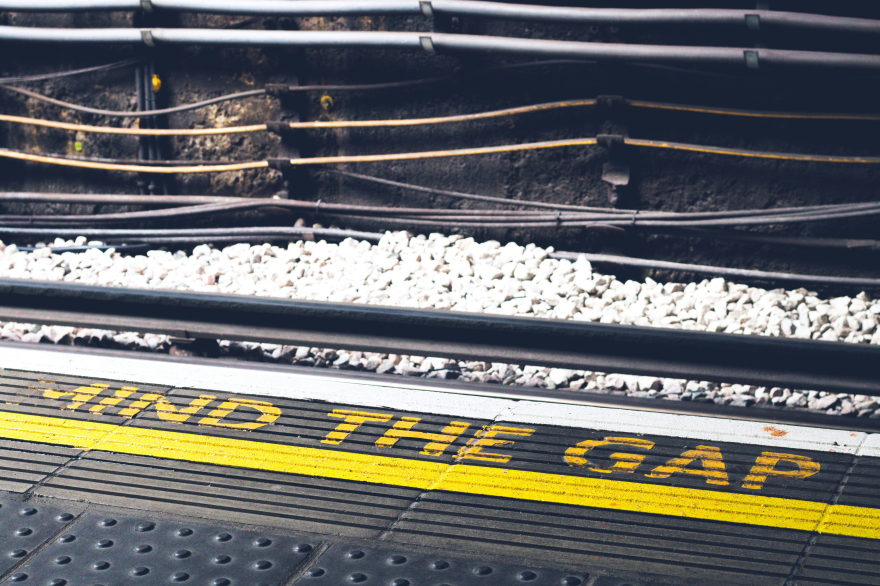 The edge of a train platform with "Mind the Gap" painted near the edge